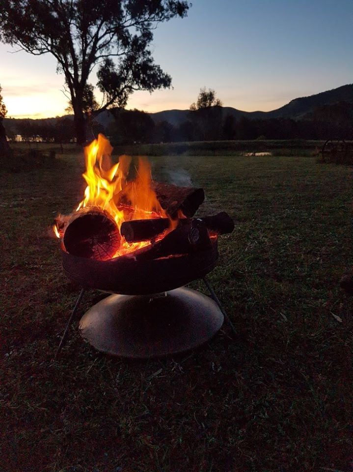 A fire pit is sitting in the middle of a grassy field at night.