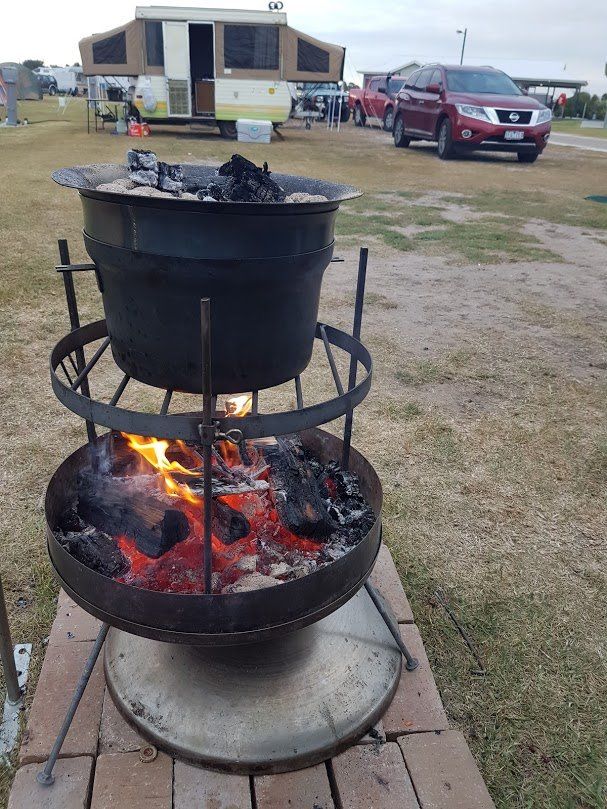 A large pot is cooking over a fire in a field.