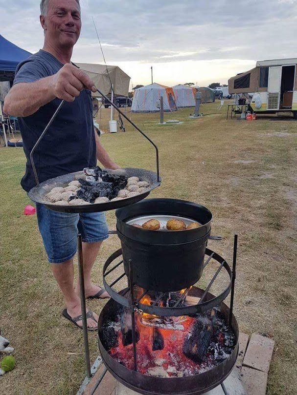 A man is cooking food over a fire pit.