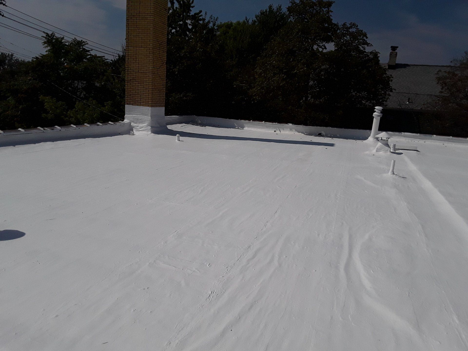 A white roof with a chimney in the background.