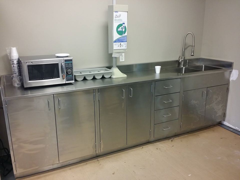 A kitchen with stainless steel cabinets , a microwave and a sink.