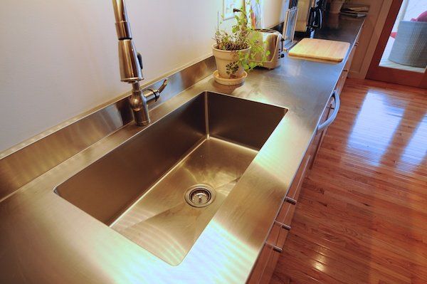 A kitchen with a stainless steel sink and faucet