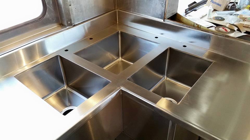 A stainless steel sink with three sinks in a kitchen.