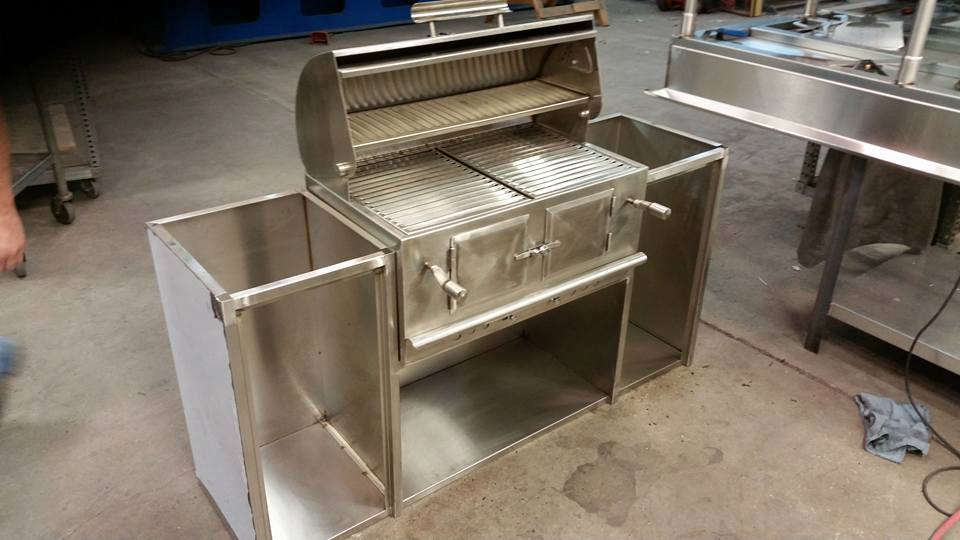 A stainless steel grill is sitting on the floor in a room.