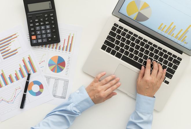 Accounting Firm — Man Using a Laptop With Graphs and Calculator in Gulfport, MS