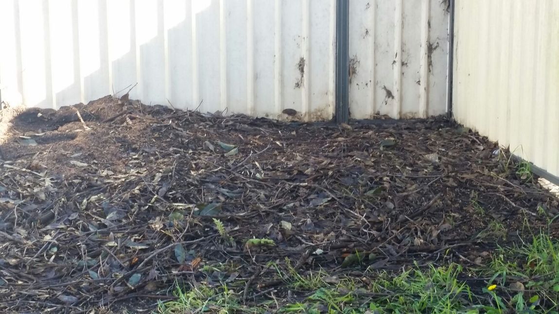 A pile of dirt is sitting next to a white fence.