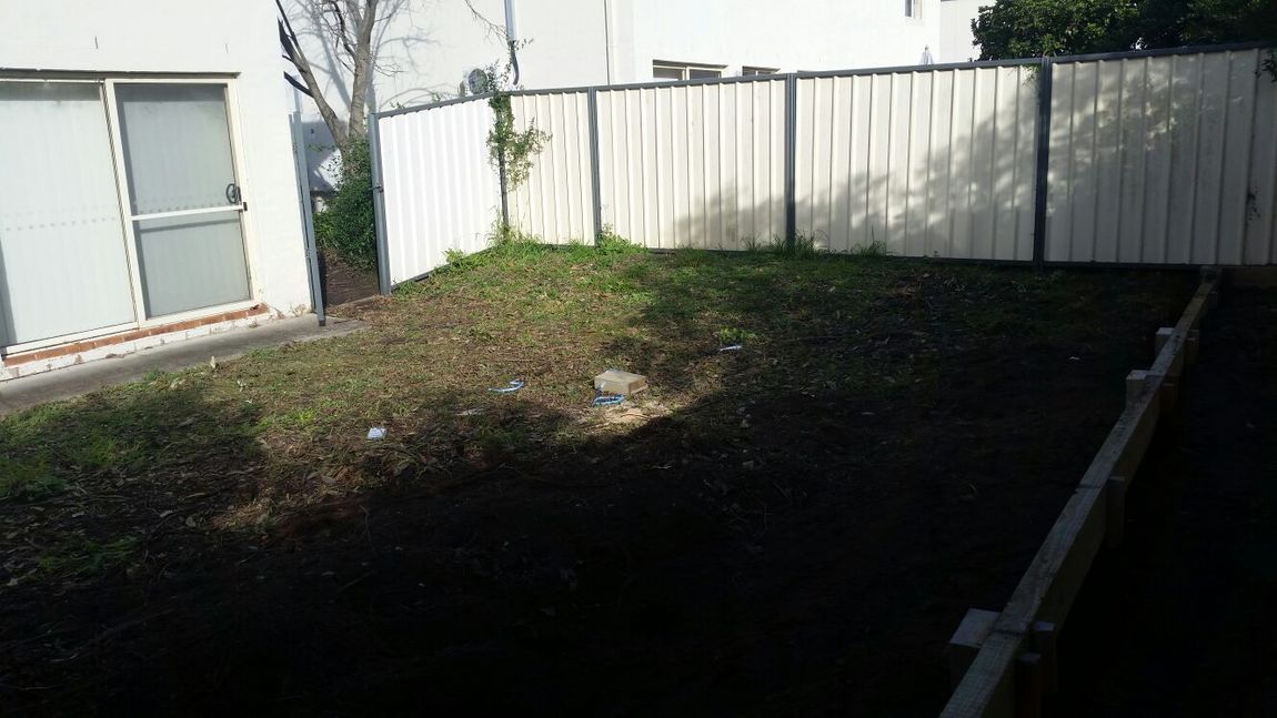 A backyard with a white fence and a sliding glass door.