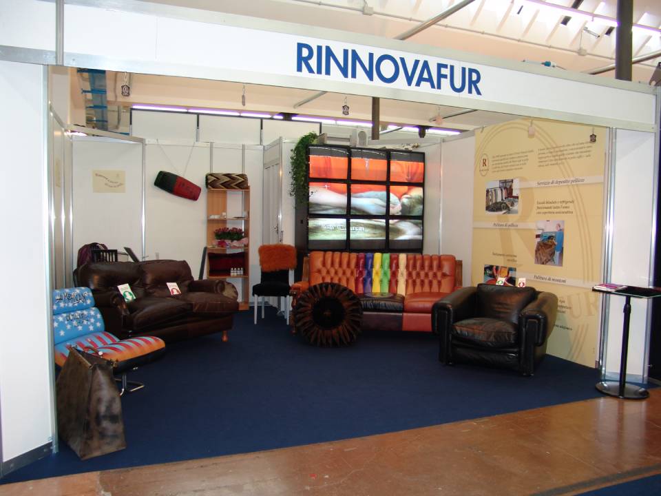 Stand Rinnovafur con divani, poltrone e cuscini decorati in un'esposizione fieristica.