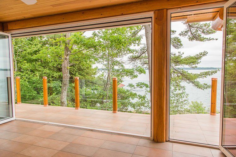 Custom Muskoka Cottage featuring a room with a view of a lake through a sliding glass door.