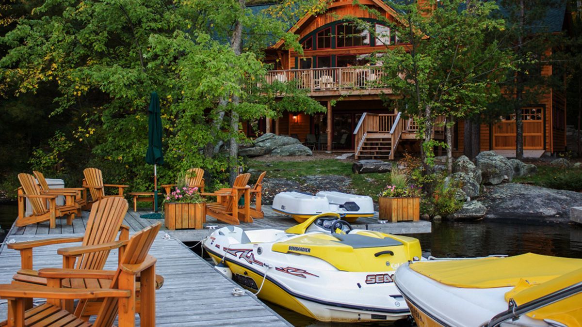 Custom Muskoka Cottage featuring a yellow jet ski is docked at a dock in front of a house.
