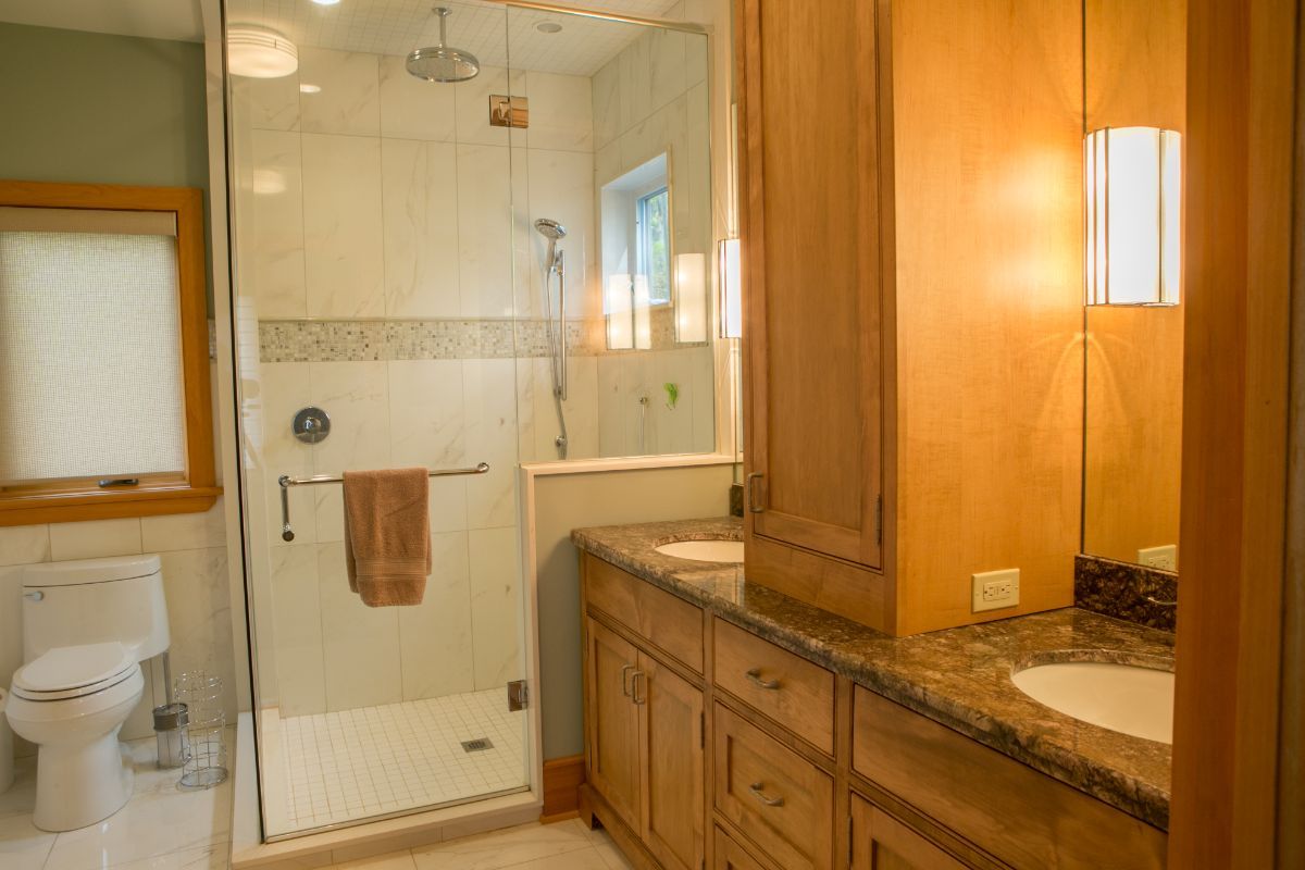 Custom Muskoka Cottage featuring a bathroom with a walk in shower , sink , toilet and mirror.