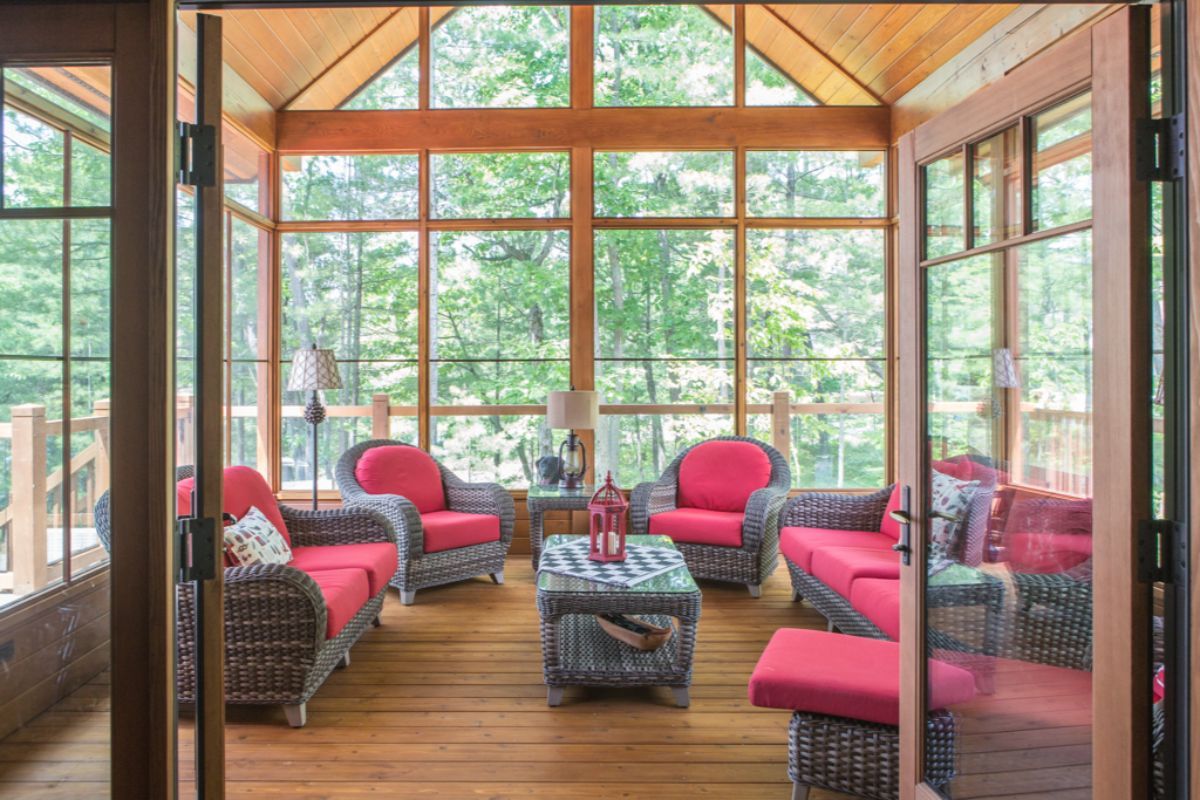 Custom Muskoka Cottage featuring a screened in porch with wicker furniture and lots of windows.