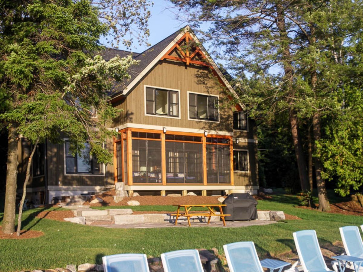 Custom Muskoka Cottage featuring a house with a screened in porch and a picnic table
