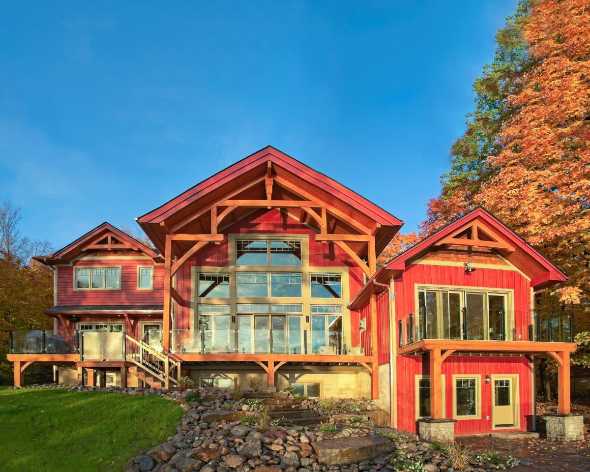 Custom Muskoka Cottage featuring a large red house with a lot of windows is sitting on top of a hill.