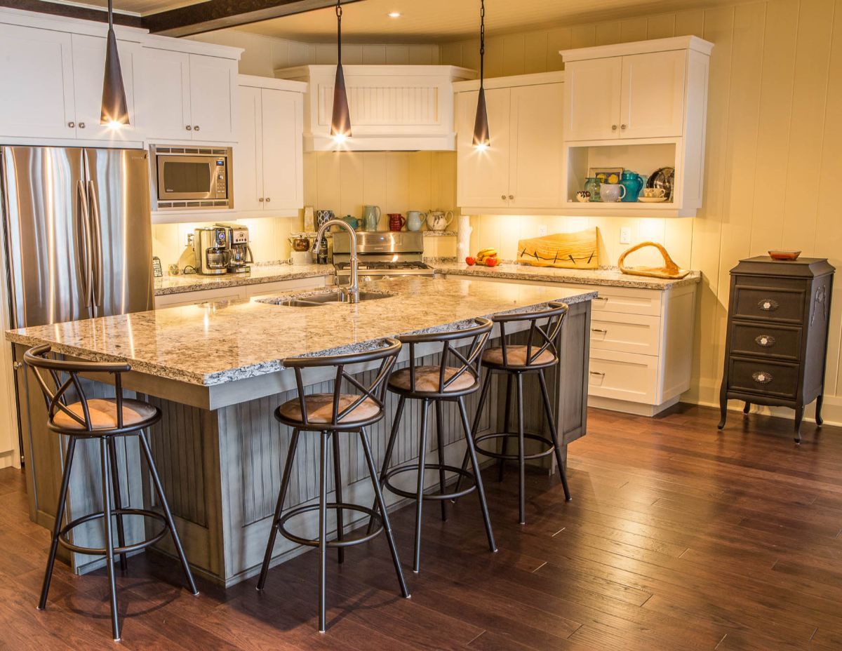 Custom Muskoka Cottage featuring a kitchen with a large island , stools and a refrigerator.
