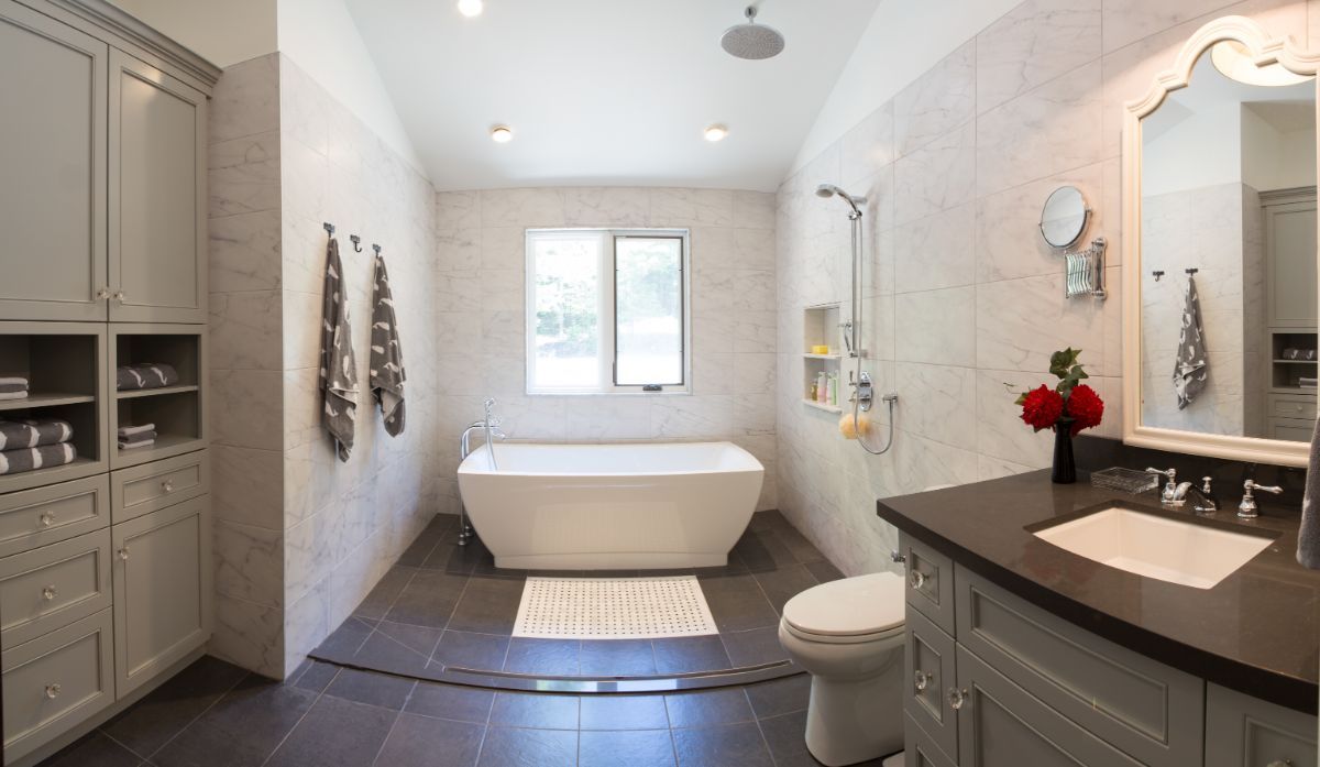 Custom Muskoka Cottage featuring a bathroom with a tub , toilet , sink and mirror.