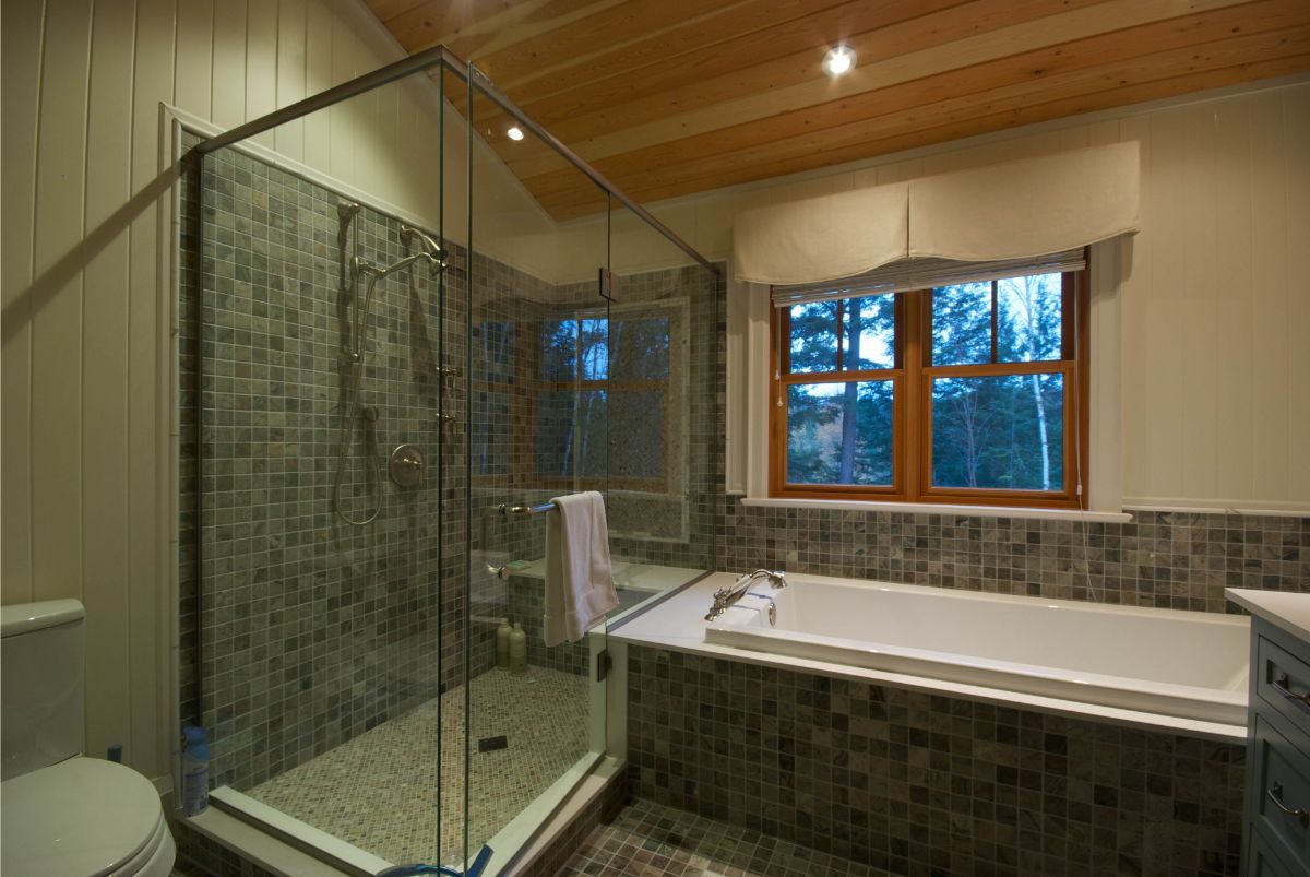 Custom Muskoka Cottage featuring a bathroom with a tub , toilet , shower and window.