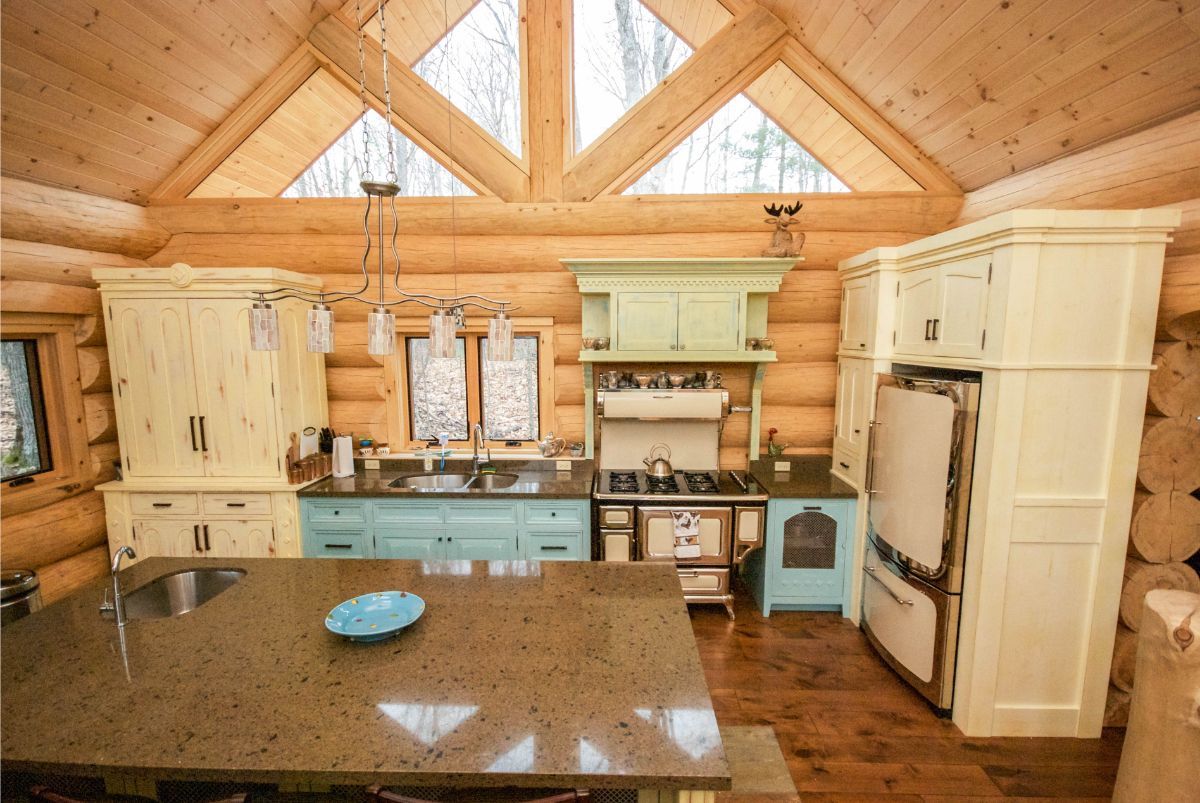 Custom Muskoka Cottage featuring a kitchen in a log cabin with white cabinets and blue appliances.