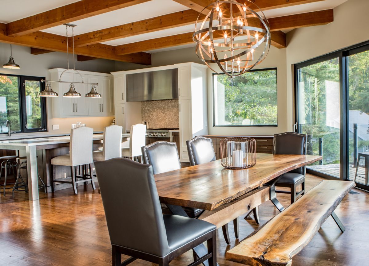 Custom Muskoka Cottage featuring a dining room with a wooden table and chairs and a bench.