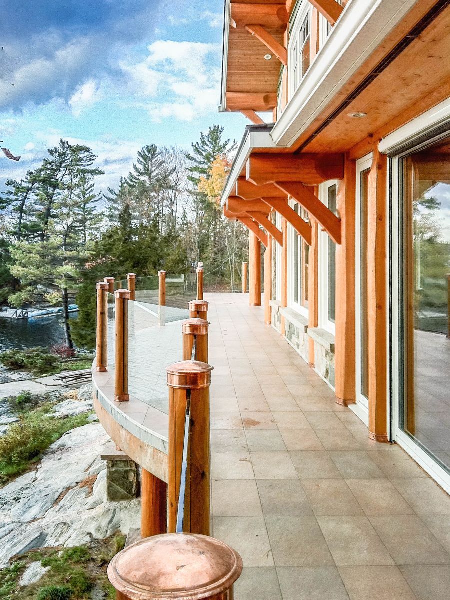 Custom Muskoka Cottage featuring a large wooden house with a large deck and sliding glass doors