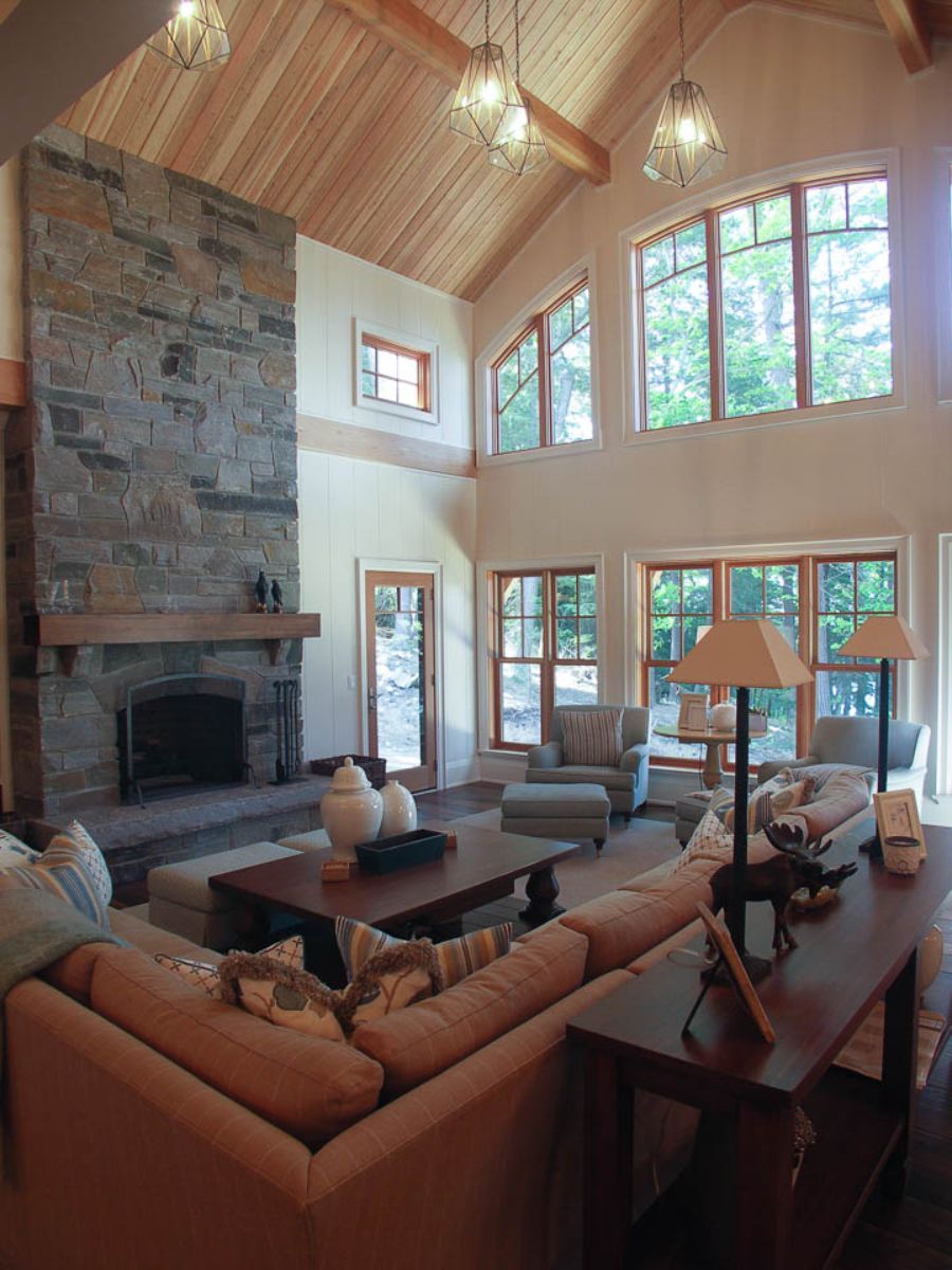 Custom Muskoka Cottage featuring a living room with a stone fireplace and lots of windows
