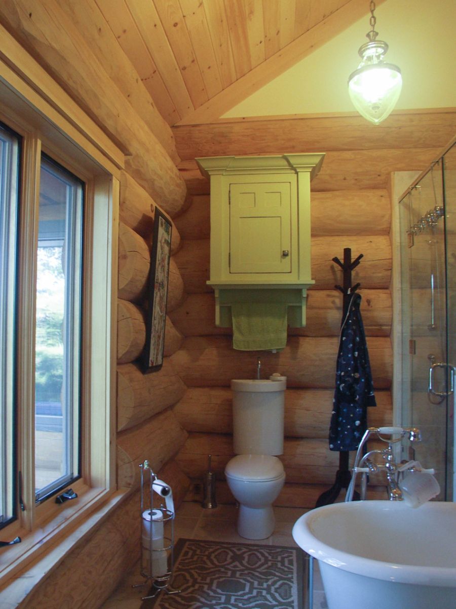 Custom Muskoka Cottage featuring a bathroom in a log cabin with a toilet and tub