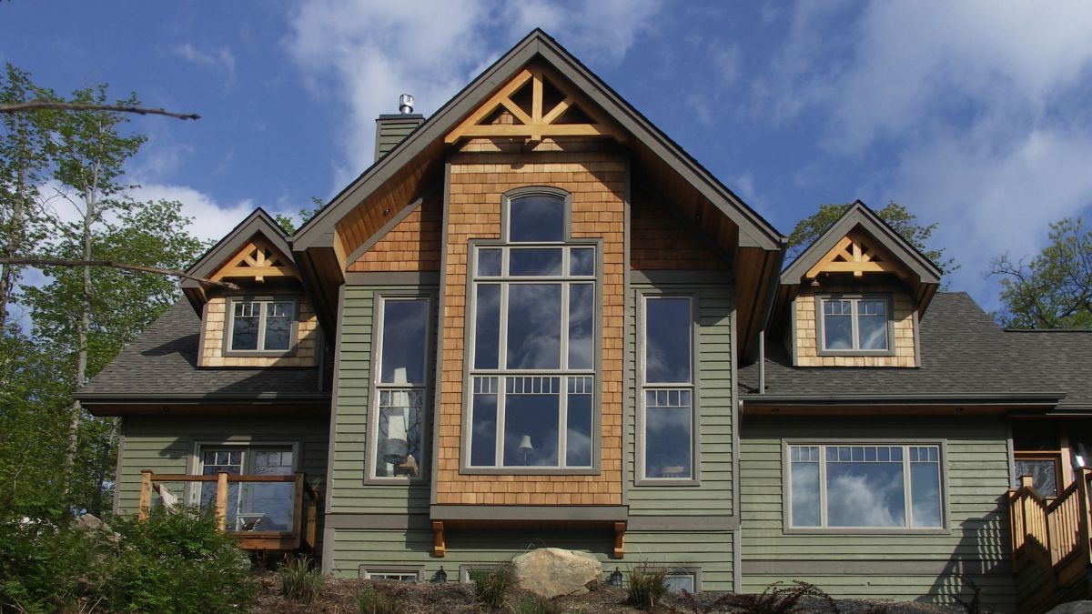 Custom Muskoka Cottage featuring a large house with a lot of windows is sitting on top of a hill
