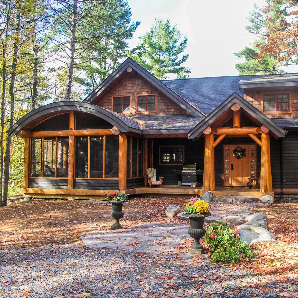 Custom Muskoka Cottage, a large house with a screened in porch in the woods