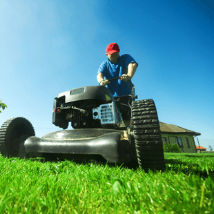 man in red cap using petrol mower