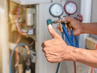 Technician Thumbs Up — Kalamazoo, MI — Suburban Heating & Air Conditioning Hand giving a thumbs-up while holding gauges and hoses connected to an air conditioning unit.