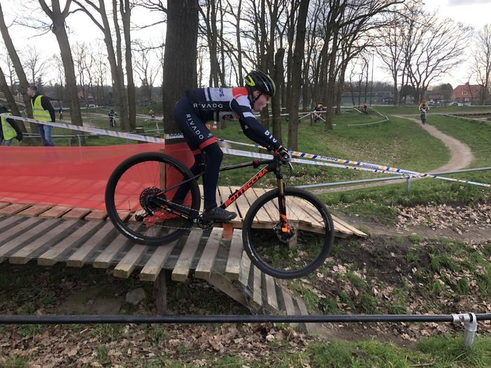 Een fietser rijdt over een houten helling op een afgezette cyclocrossbaan in een park.