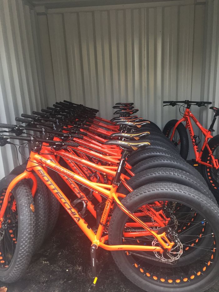 Rijen oranje fatbike's opgesteld in een zeecontainer.