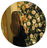 A woman is decorating a christmas tree with seashells.