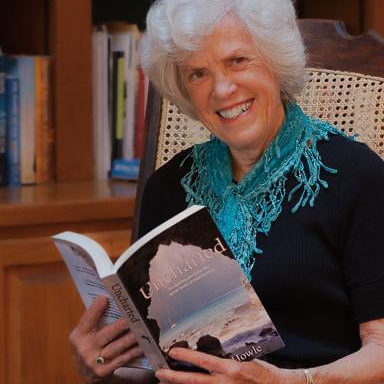 A woman is sitting in a chair reading a book called uncharted