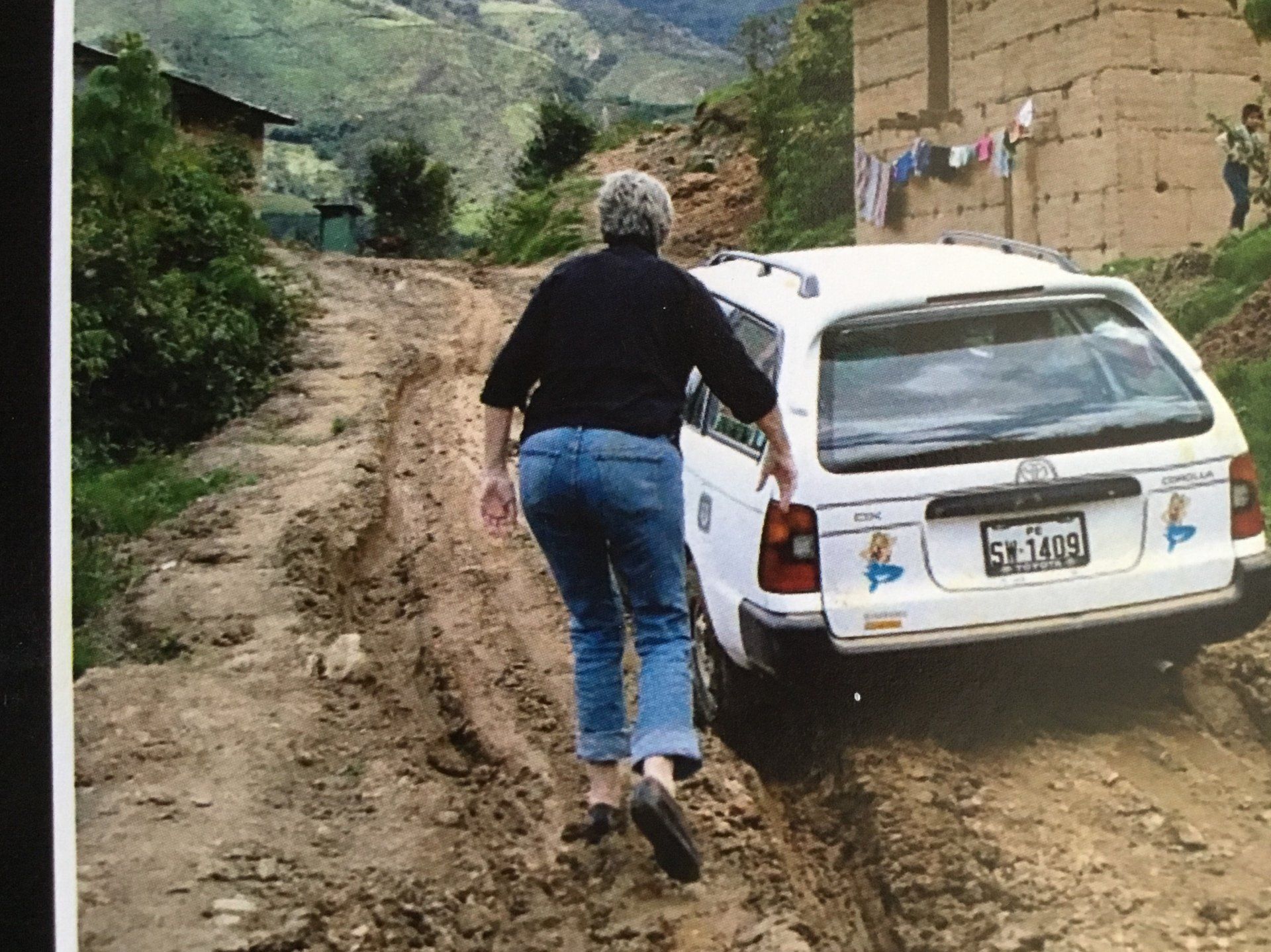 carolyn wasik in peru pushing a car stuck in the mud