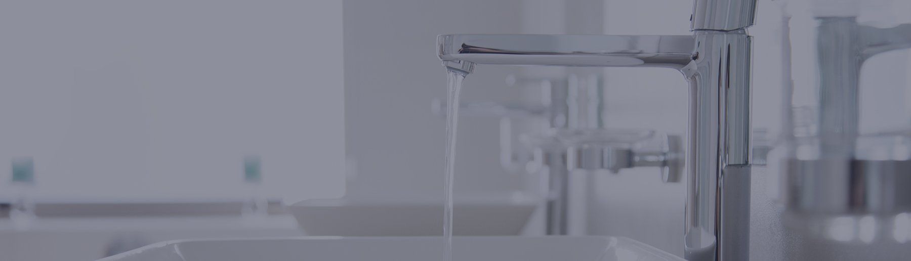 A row of chrome bathroom faucets with water flowing into sinks.
