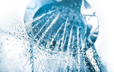 Shower head with water spraying out, close-up with blue and white color scheme.