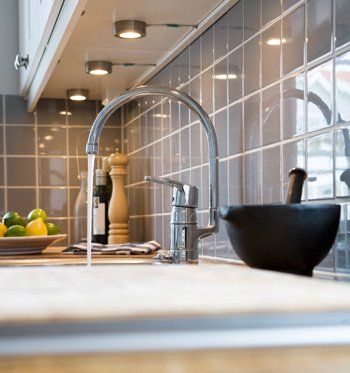 kitchen plumbing Kitchen sink with running water, gray tiled backsplash, and recessed lighting.