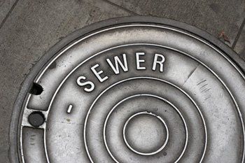 Close-up of a silver sewer cover with the word 