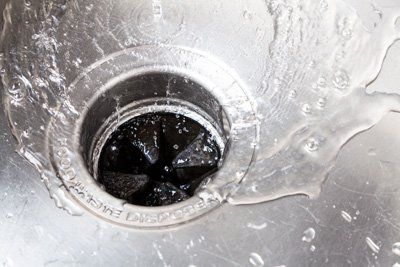 video inspection Water flowing into a stainless steel sink drain with a garbage disposal.
