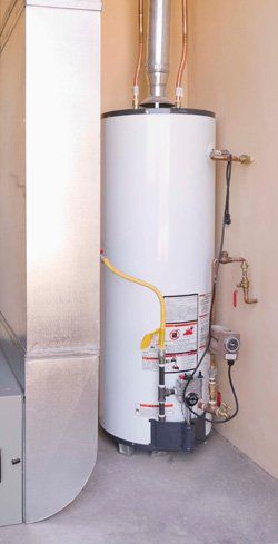 hot water heater White water heater and vent pipe in a utility closet with a concrete floor.
