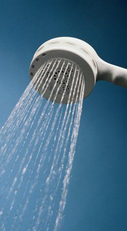 hot water White shower head spraying water against a clear blue sky.