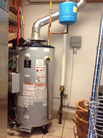 commercial plumbers A natural gas water heater with copper pipes, vent, and a blue expansion tank in a utility room.