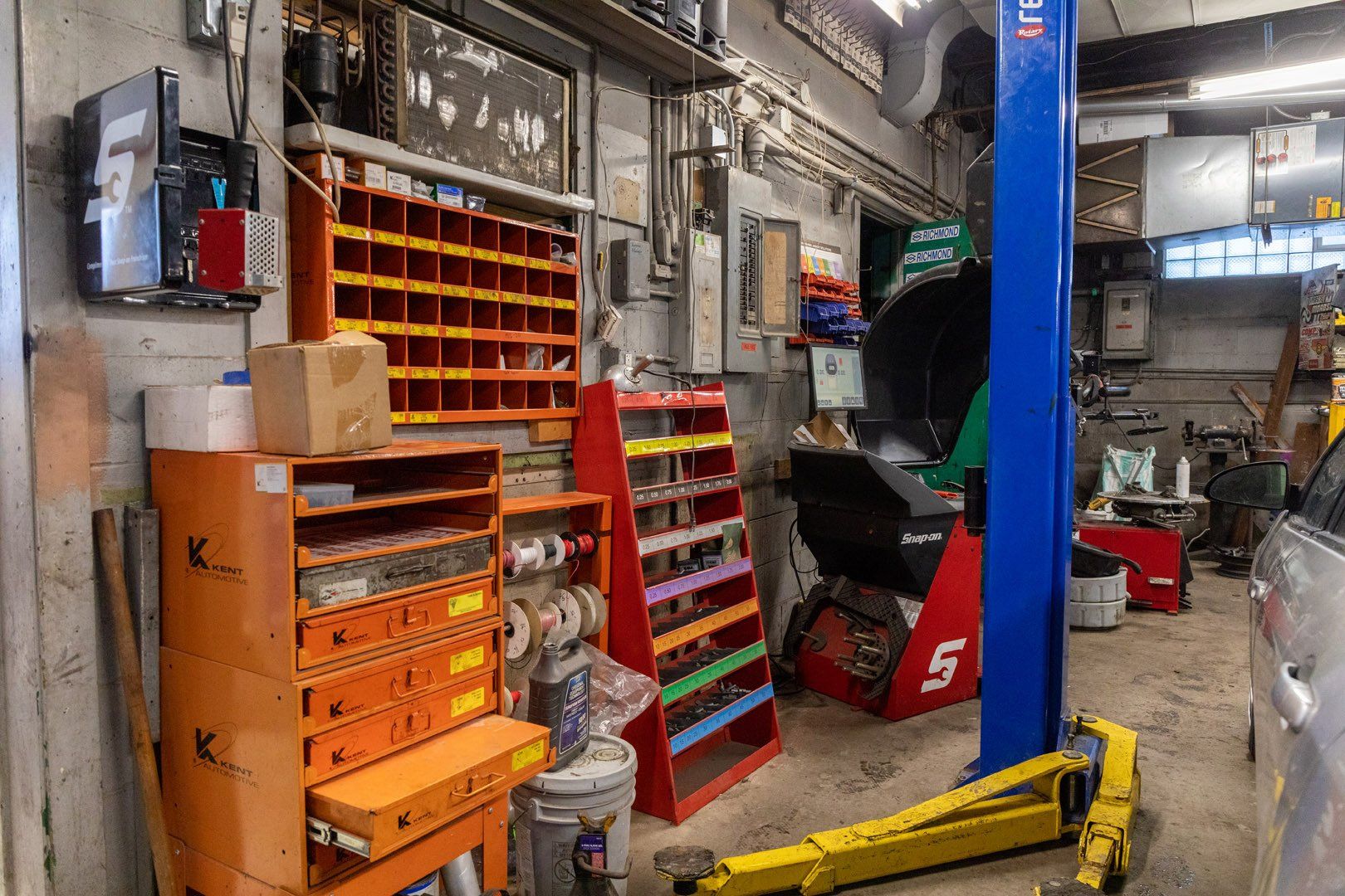 An auto repair shop interior: tools, parts shelves, lift, and a car.