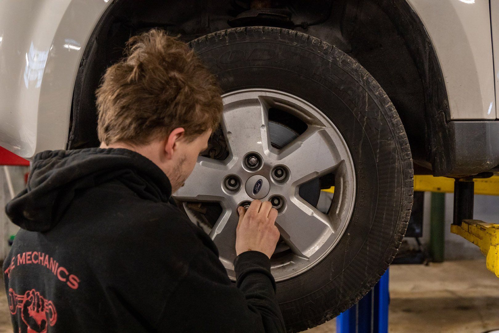 Mechanic working on a car tire, in a garage.