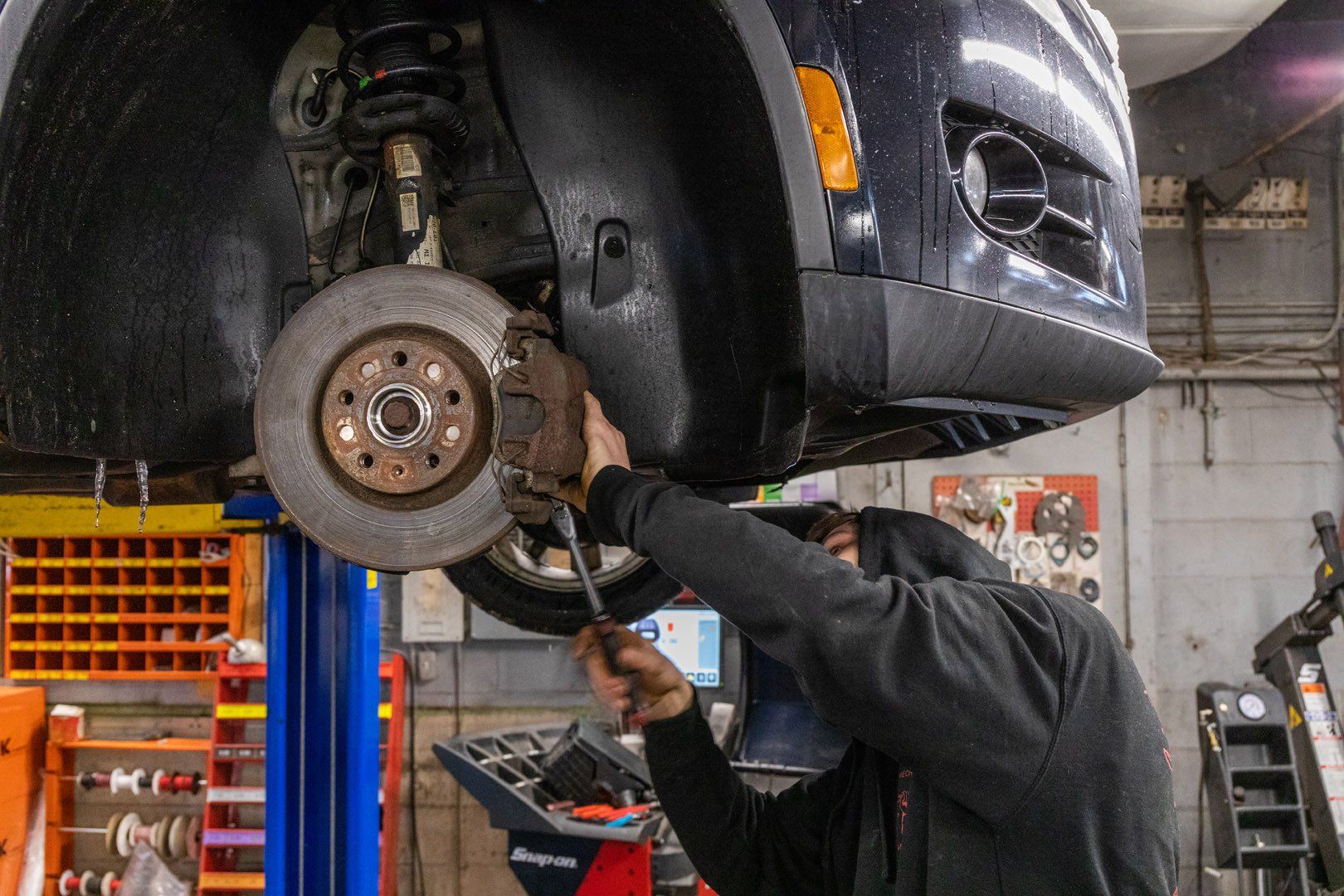 Mechanic working on a car's brake system in a repair shop.