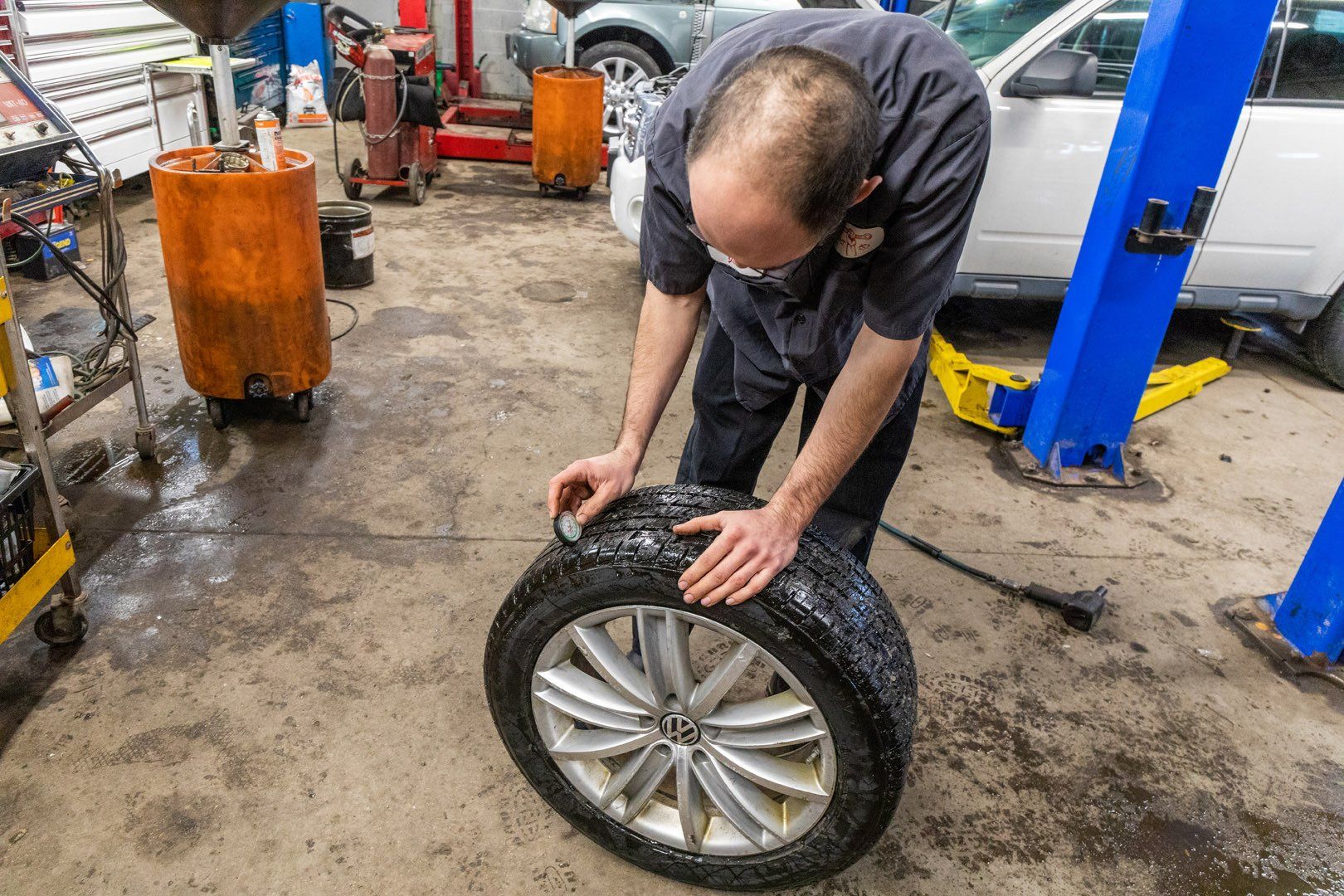 Mechanic cleaning a car tire in a garage, using a brush.