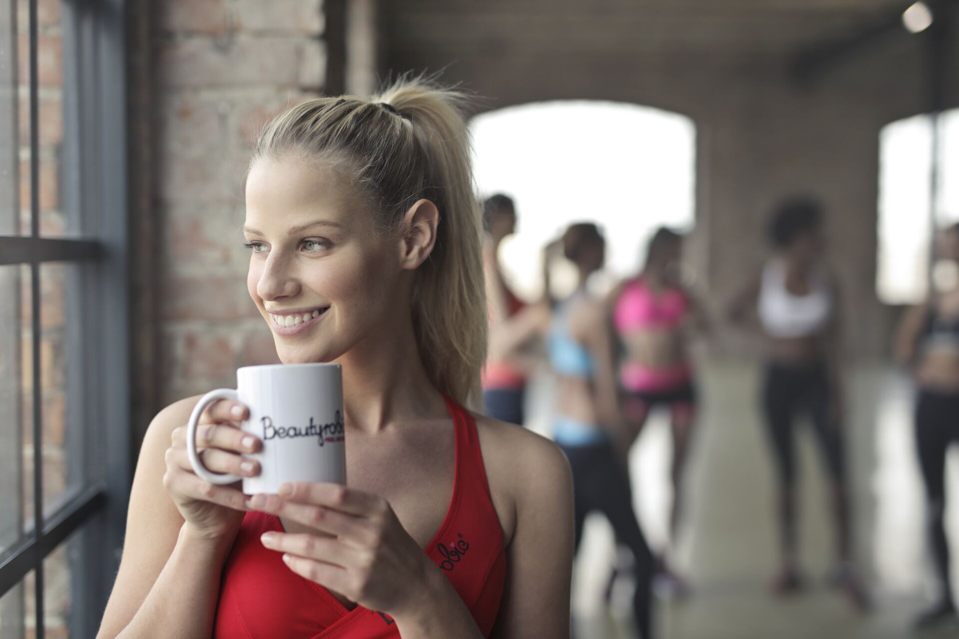 A woman is holding a cup of coffee in a gym.