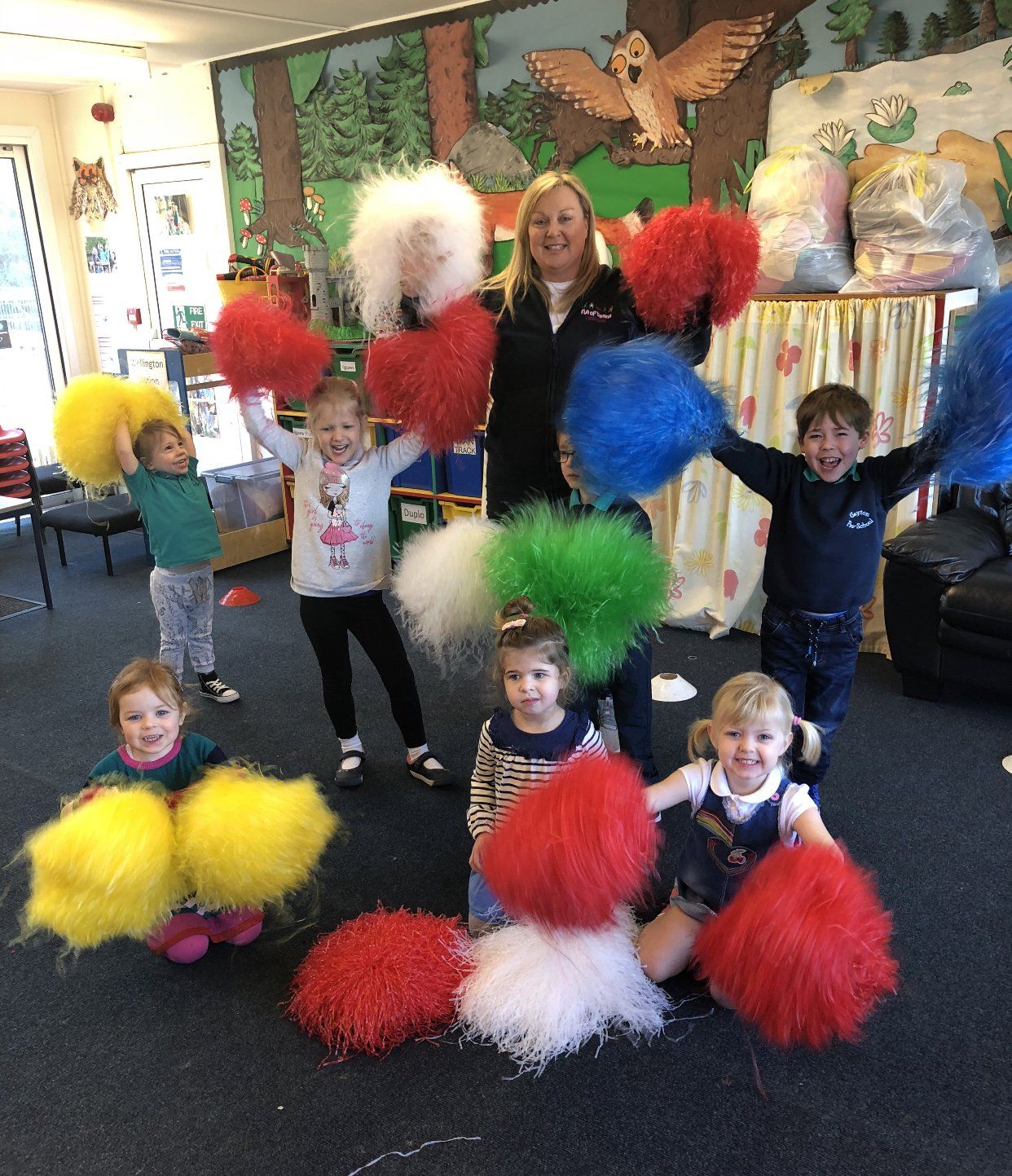 A group of children holding up pom poms in a room