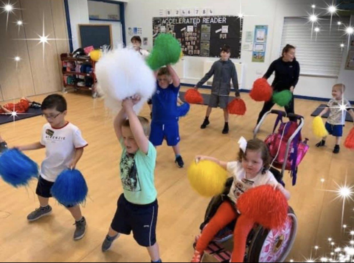 A group of children are playing with pom poms in a gym